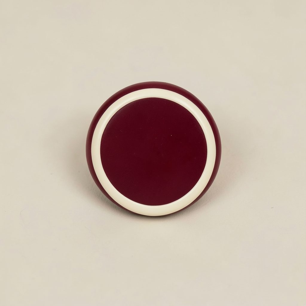 Small circular COMP emblem in burgundy and cream